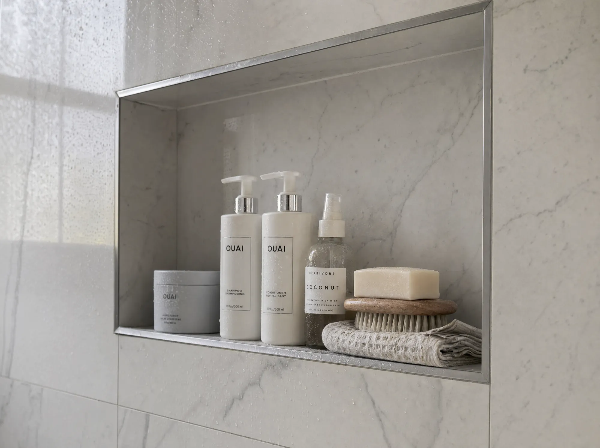 Close-up of a recessed tiled shower niche with marble-look tile