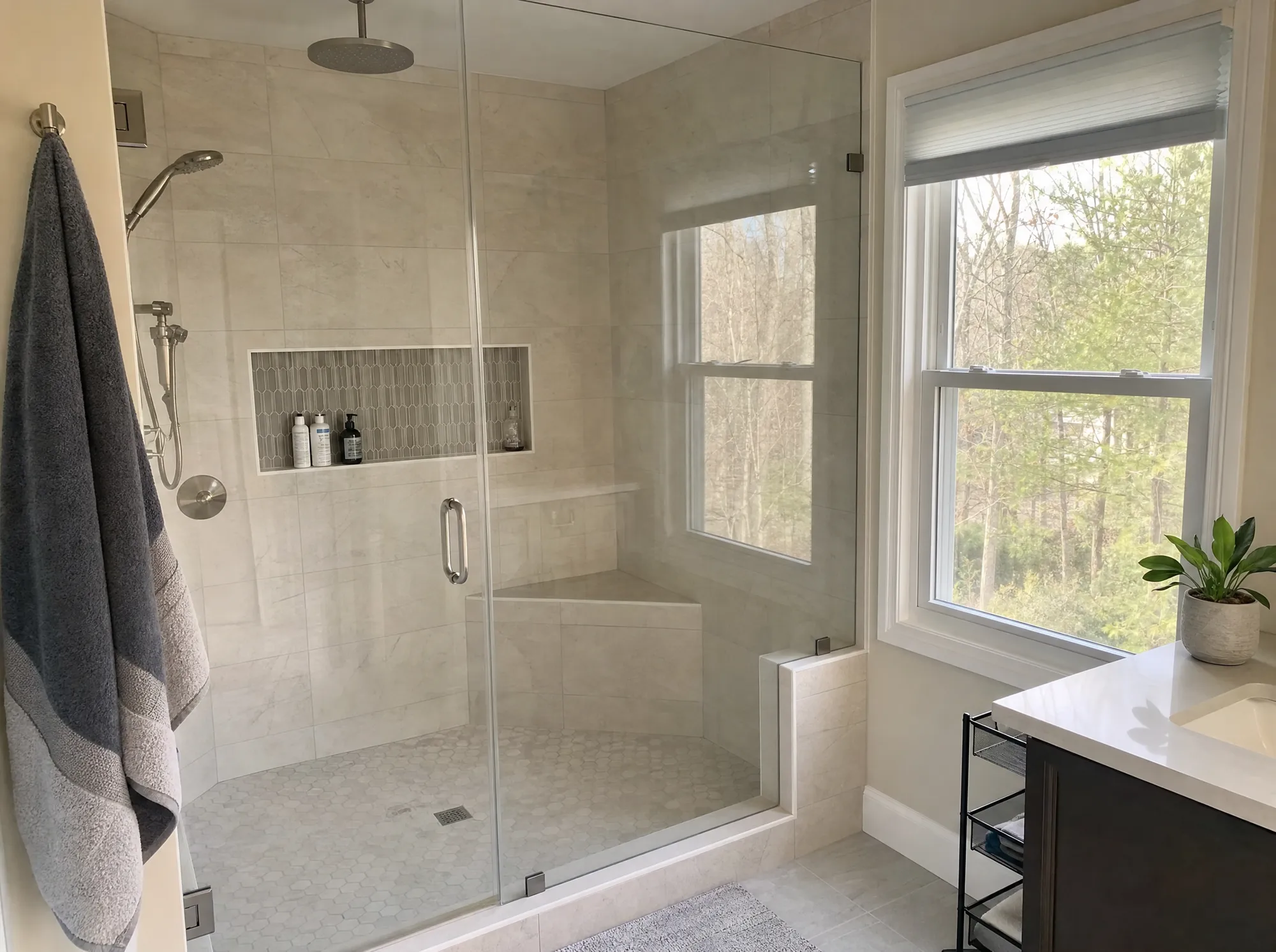 Walk-in tiled shower with a frameless glass enclosure and a recessed niche