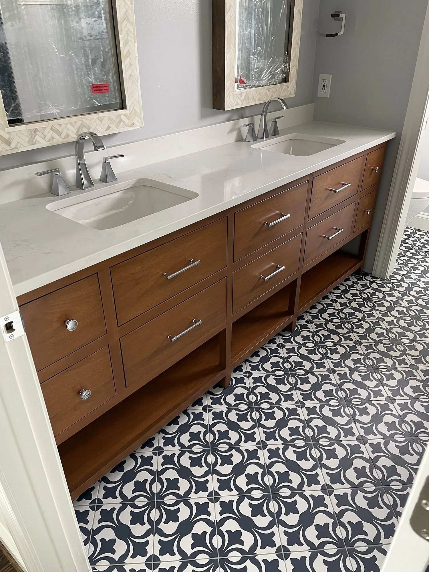 Side view of a wood double vanity with drawer stacks and patterned cement floor tile