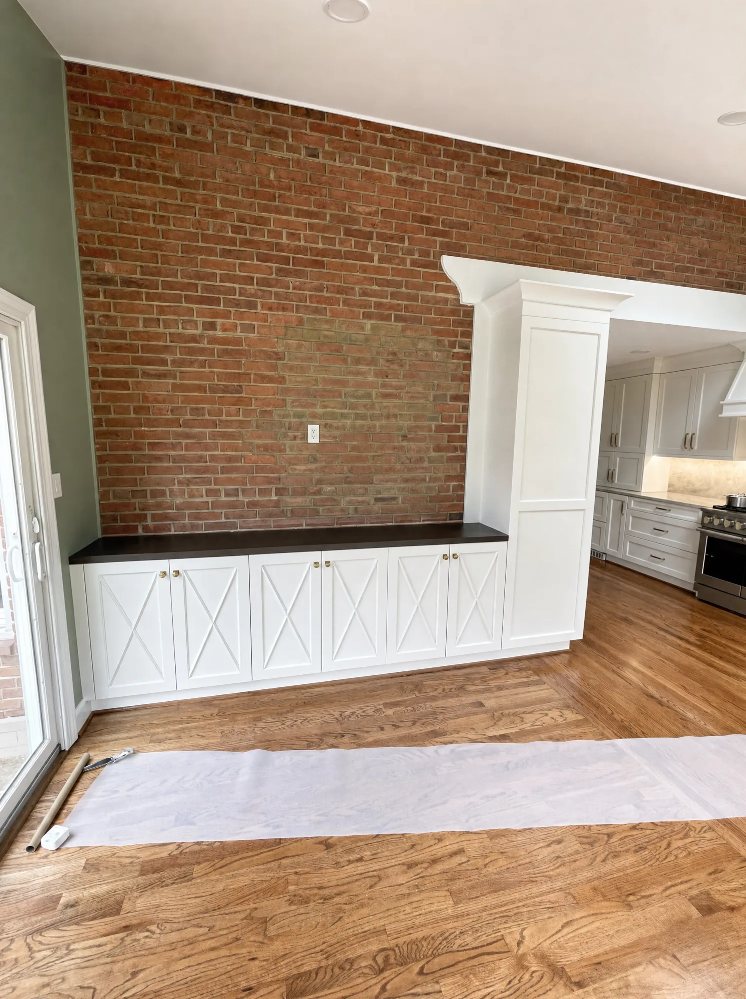 Custom white X-panel bench banquette against an exposed-brick wall by Fogg Carpentry