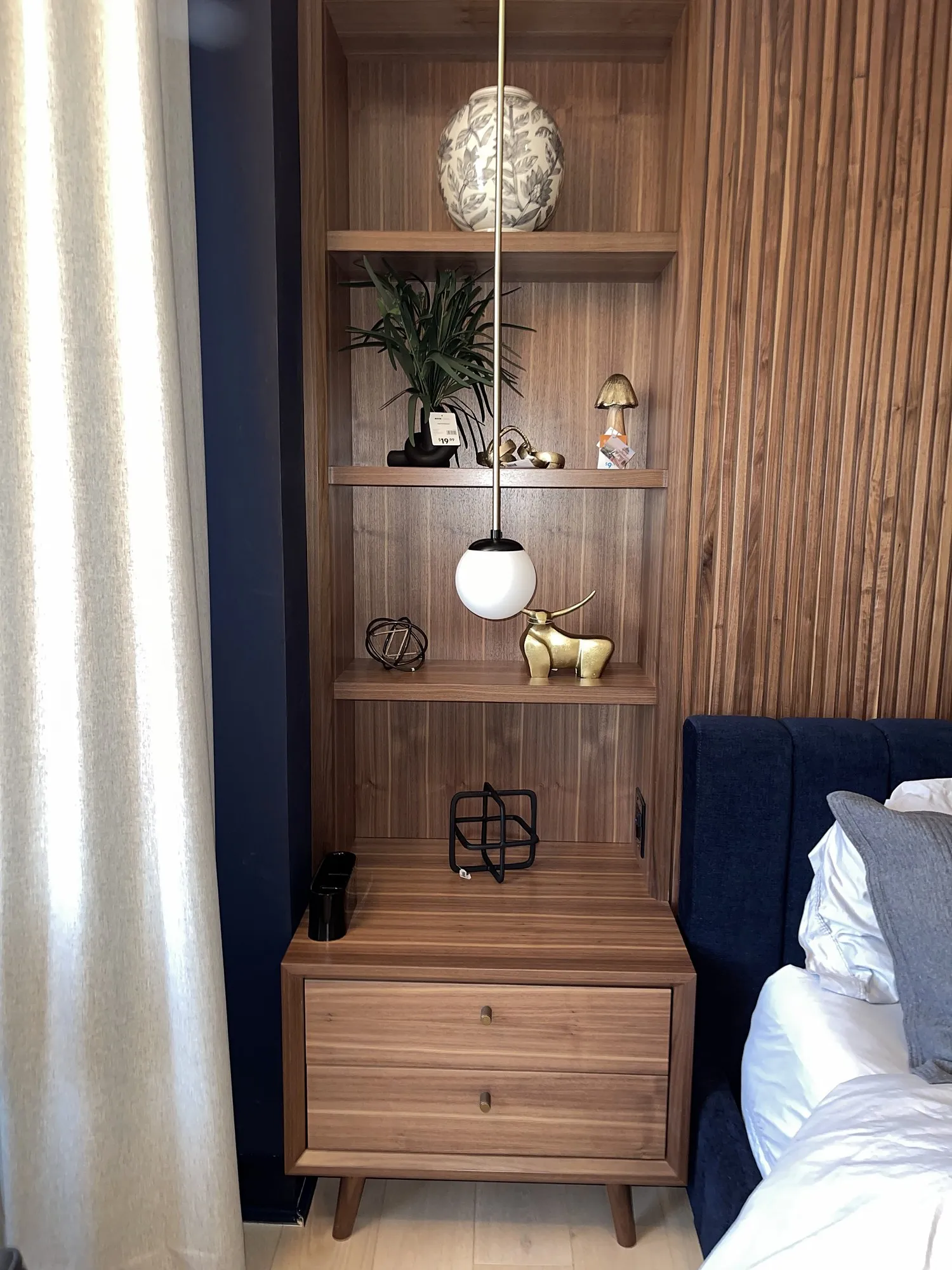 Walnut slat paneling with floating walnut shelves beside a bed
