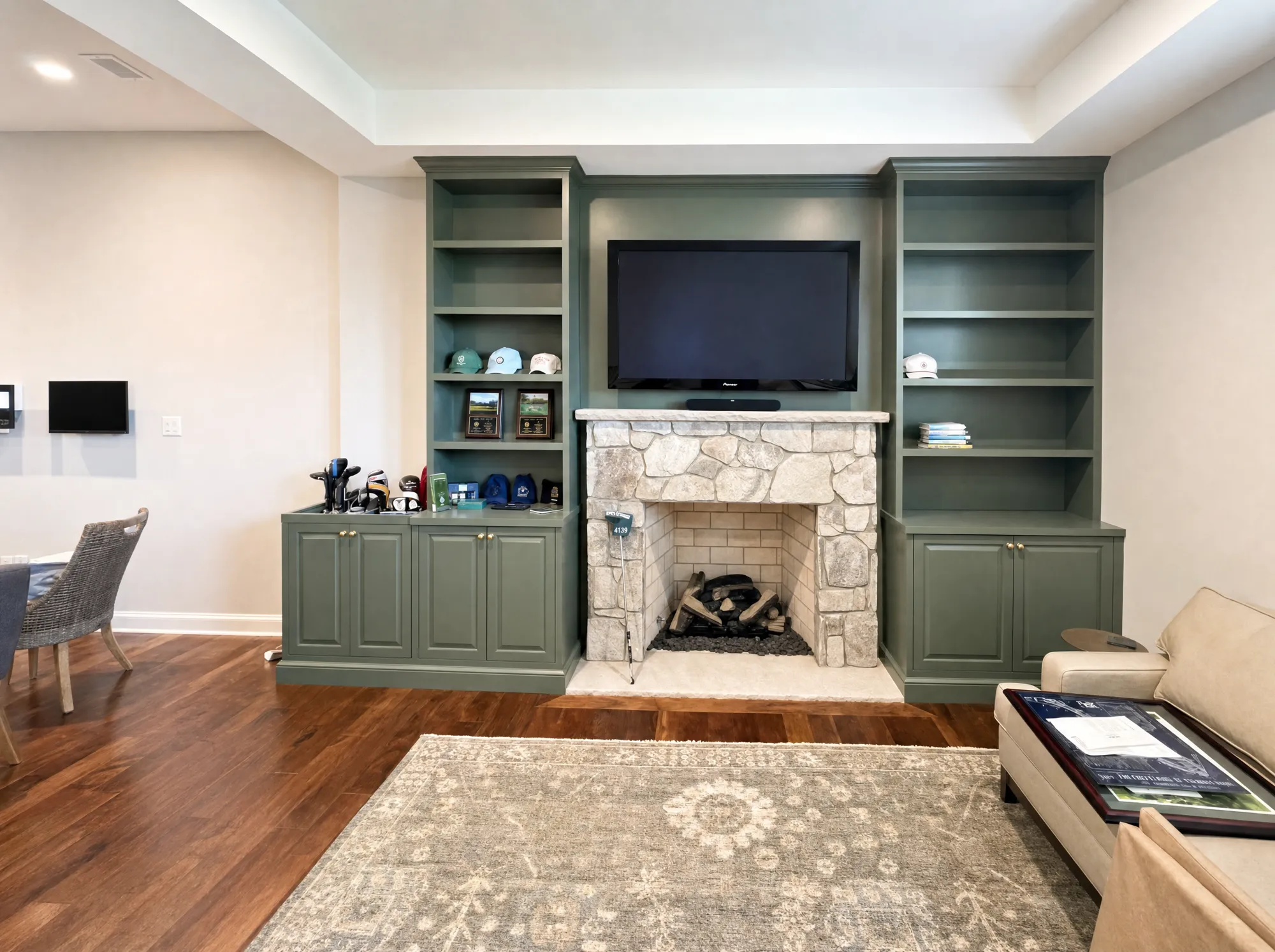 Whole-room remodel with sage-green built-ins flanking a stone fireplace