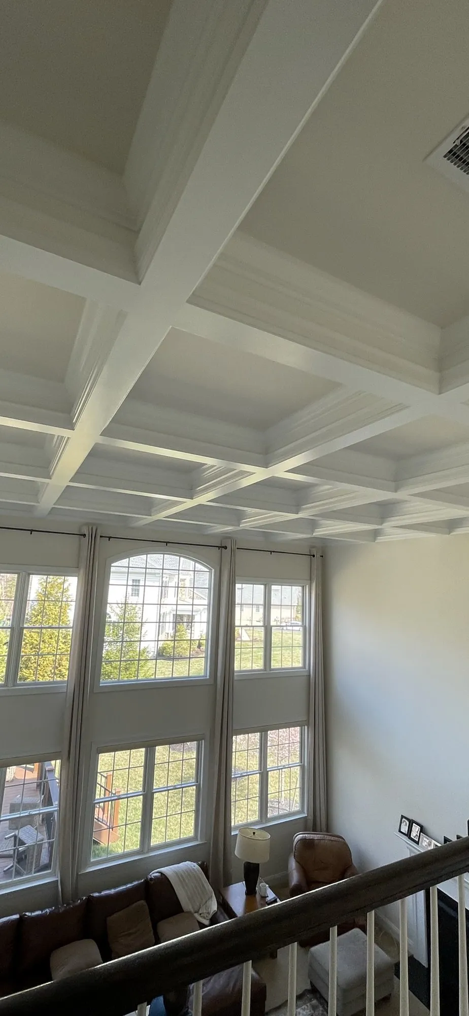 White coffered ceiling with deep beams over a two-story great room with tall windows