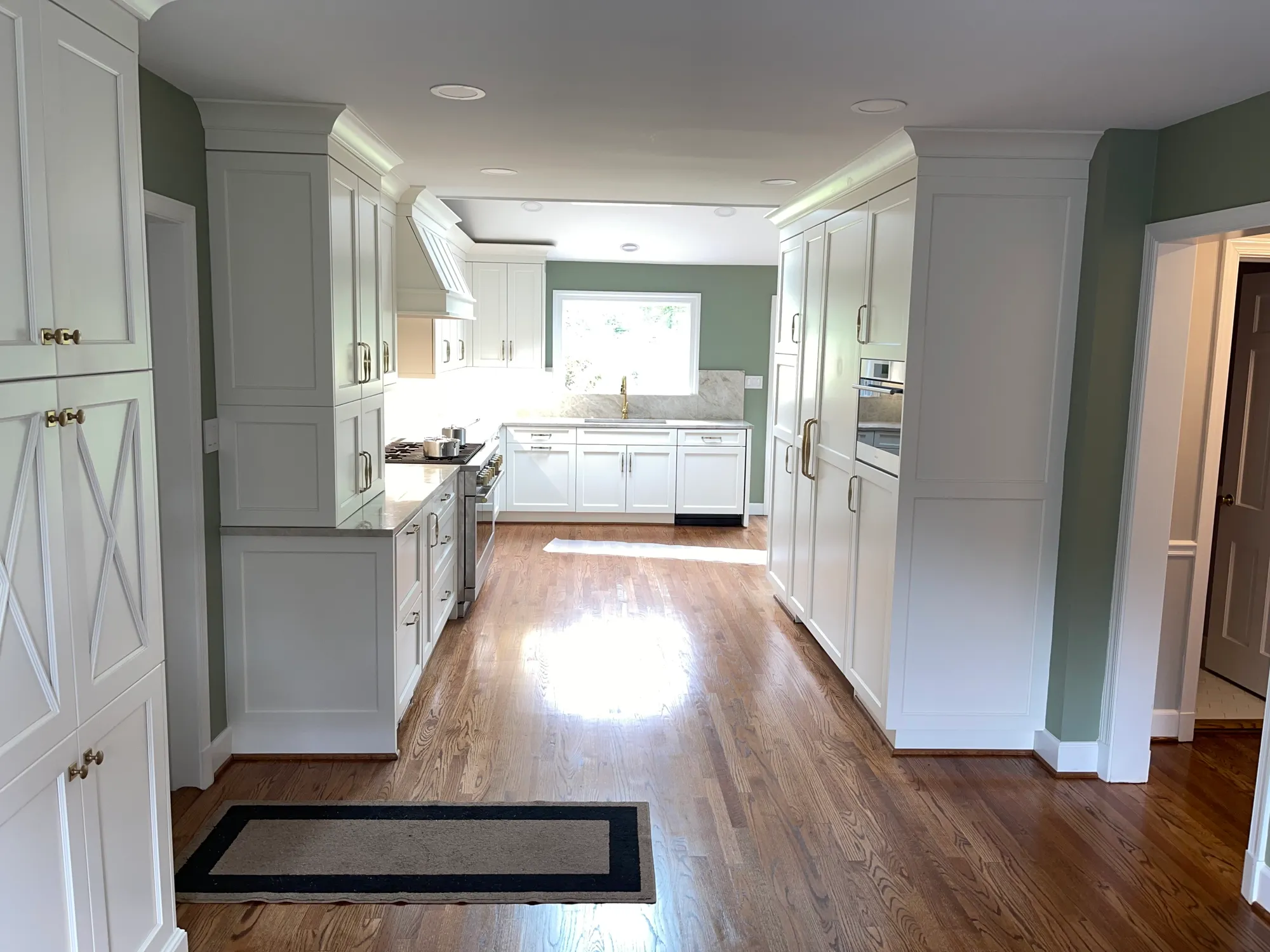 Finished white-cabinet kitchen remodel with hardwood floors and marble counters by Fogg Carpentry in Rockville, MD