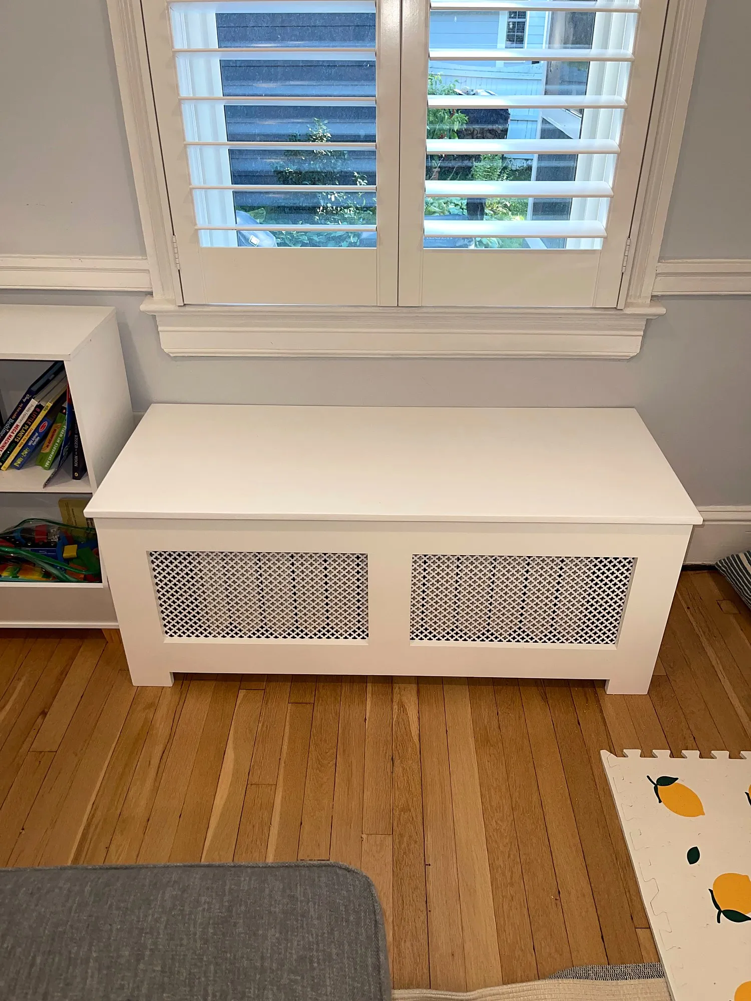 Custom white radiator bench cover with lattice grilles installed under a shuttered window