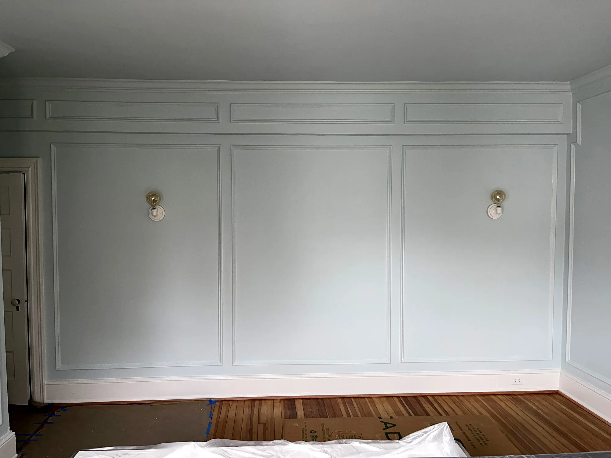 Full wall of white picture-frame molding with a frieze band of small panels below the crown