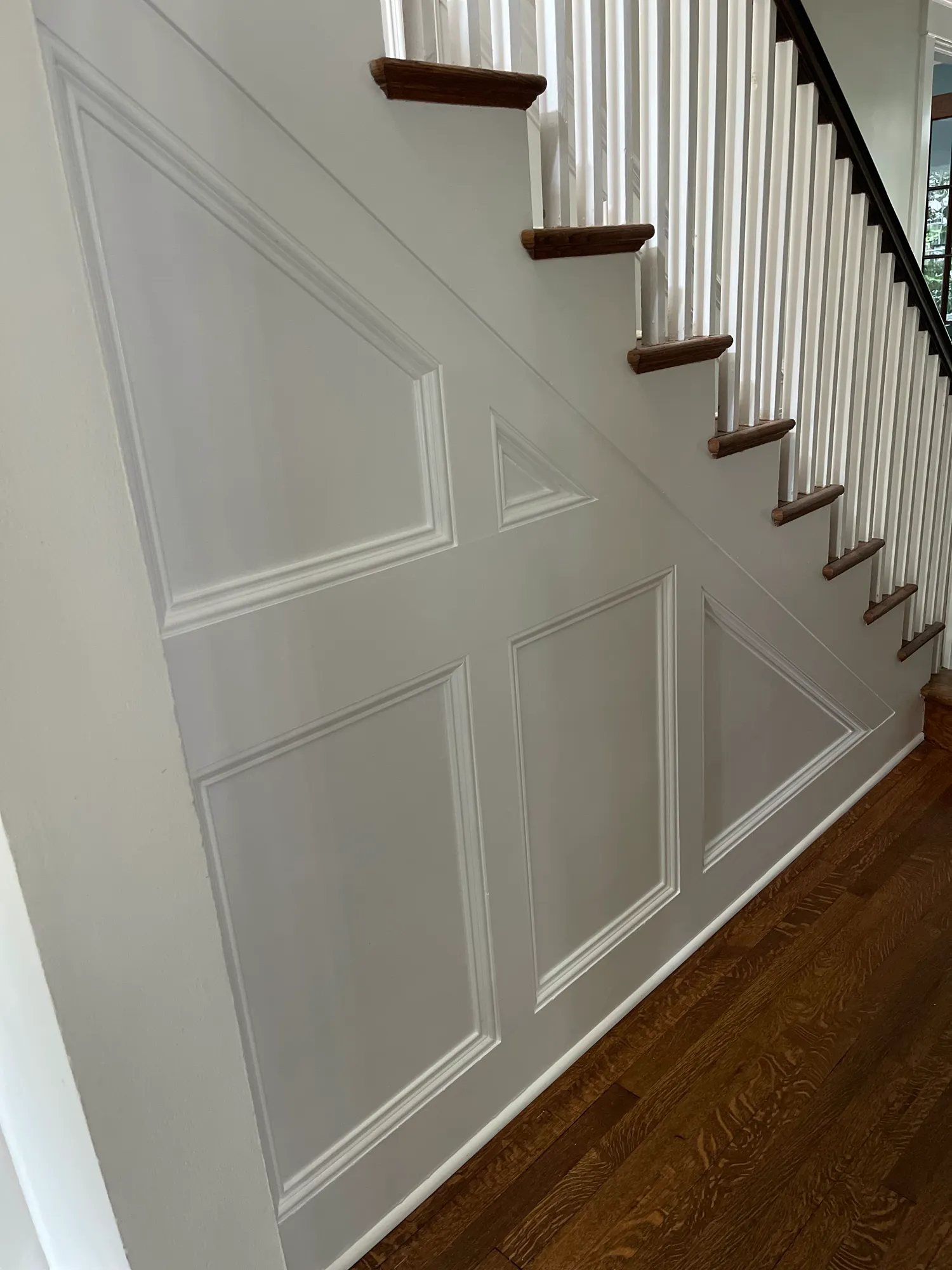 White picture-frame paneling following the underside of a staircase
