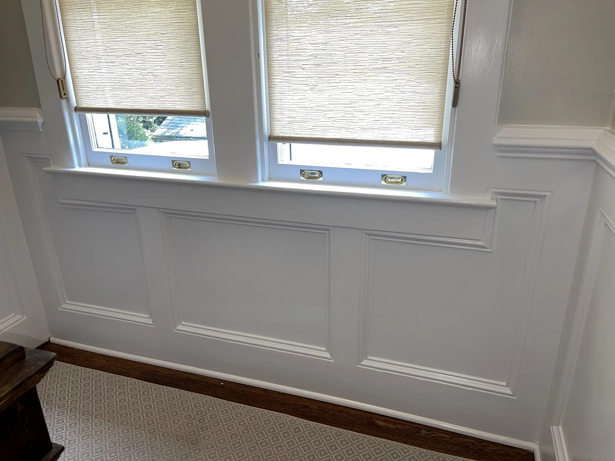 White paneled wainscoting along a wall beneath a pair of windows